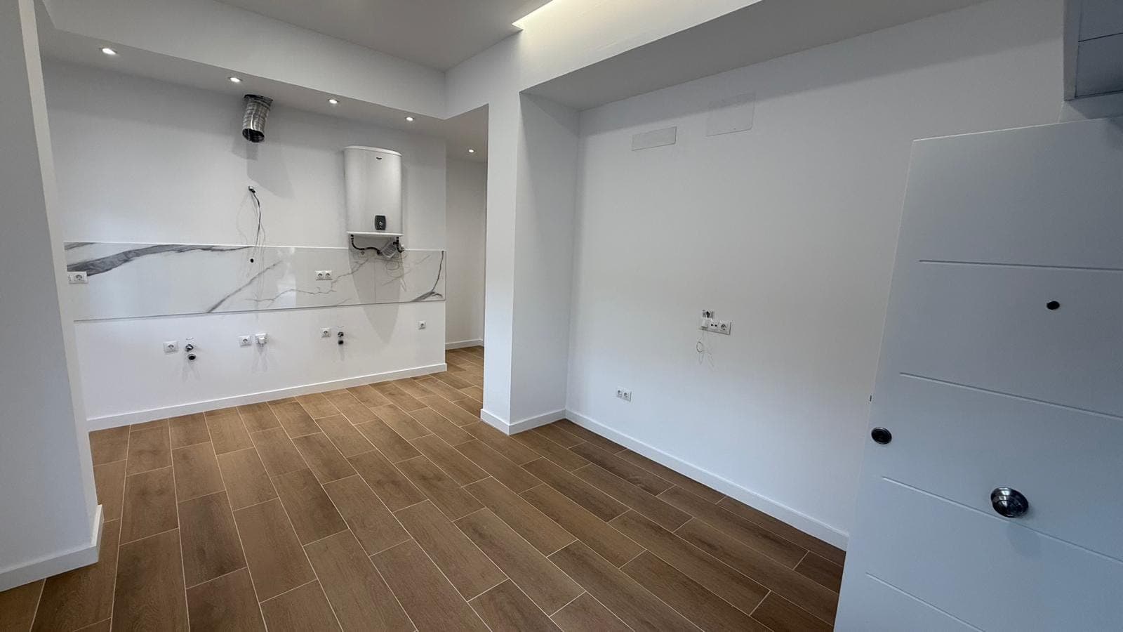 Salón-comedor-cocina terminado, con solería tipo madera e iluminación empotrada
